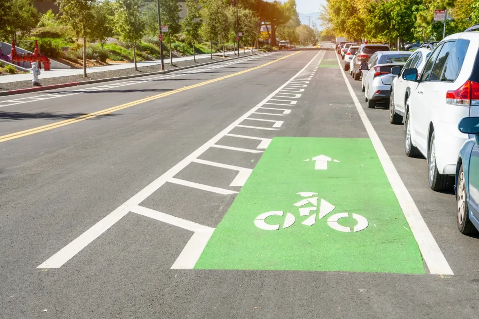 Green painted bike lane with striped buffer between car lane and curb parking lane.